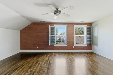 a view of empty room with wooden floor and fan