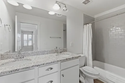 a bathroom with a granite countertop sink a toilet and a mirror