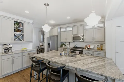 a kitchen with kitchen island granite countertop a sink and microwave