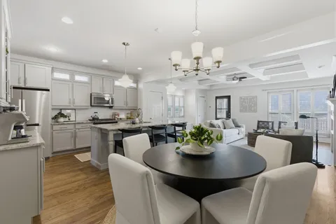 a view of a dining room and livingroom with furniture wooden floor a chandelier