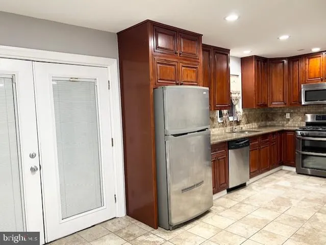 a kitchen with kitchen island granite countertop wooden cabinets a refrigerator and a sink
