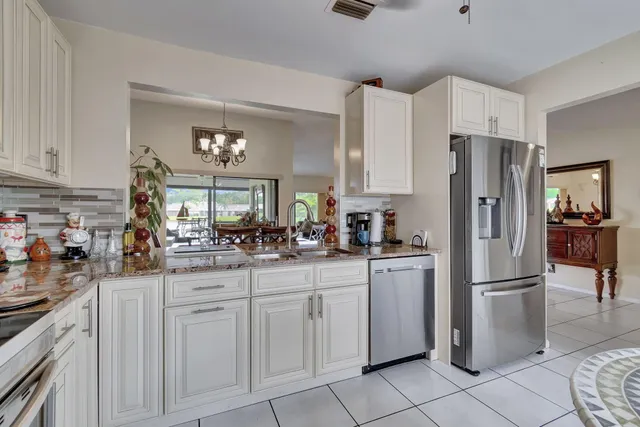 a kitchen with white cabinets and refrigerator