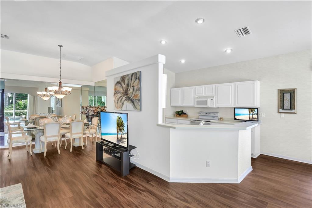 1721 Marsh Run Naples, FL 34109 - Photo 15 of 35 a kitchen with stainless steel appliances granite countertop a stove top oven a refrigerator a dining table and chairs with wooden floor