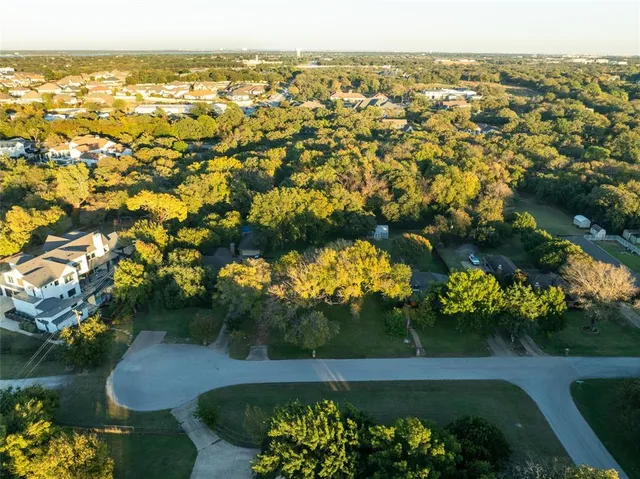 an aerial view of a residential houses with outdoor space and trees