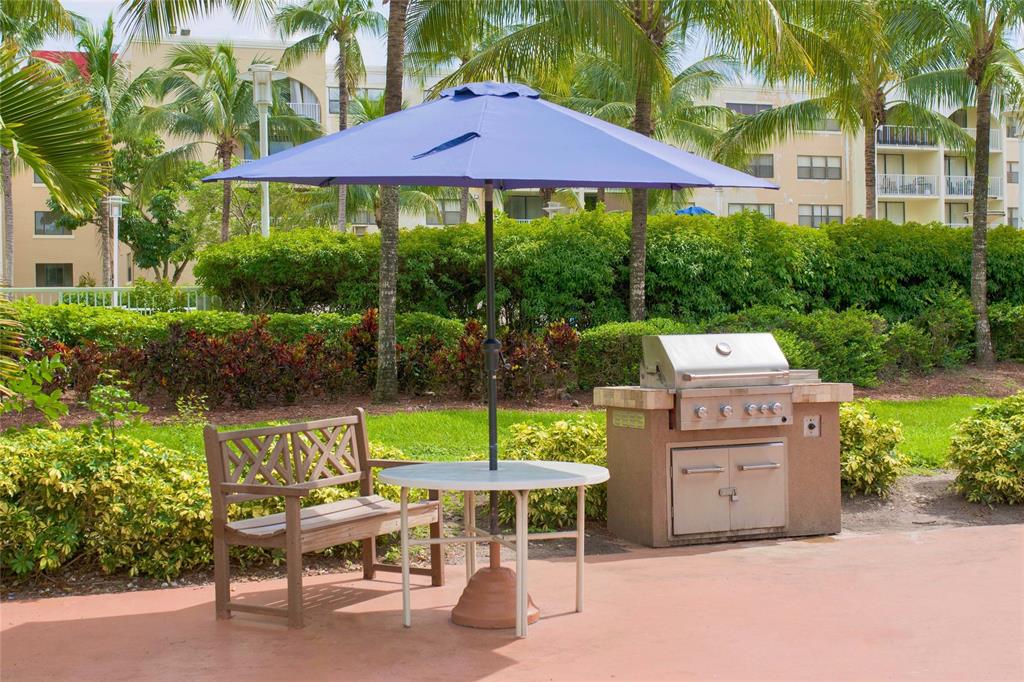 18335 Northwest 68th Avenue, Unit 245208 Hialeah, FL 33015 - Photo 15 of 18 a view of a chairs and table under an umbrella in front of house