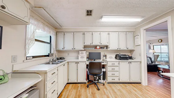 a view of a kitchen counter space a sink wooden floor and a window