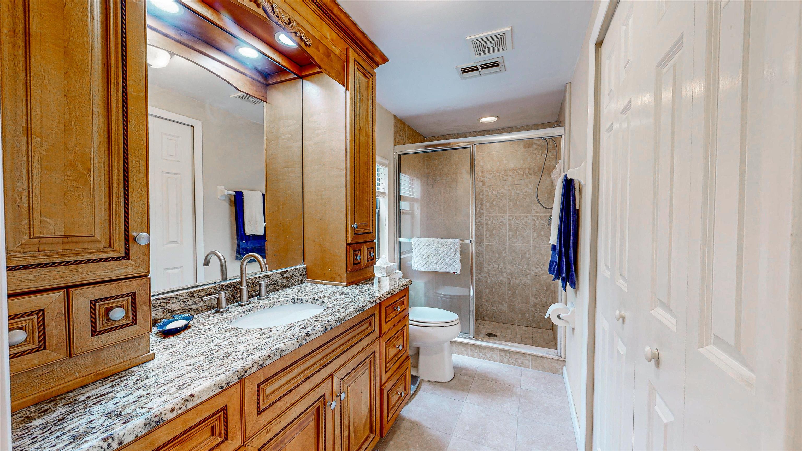 224 Puebla Road St. Augustine, FL 32080 - Photo 13 of 32 a bathroom with a granite countertop sink a mirror and a shower