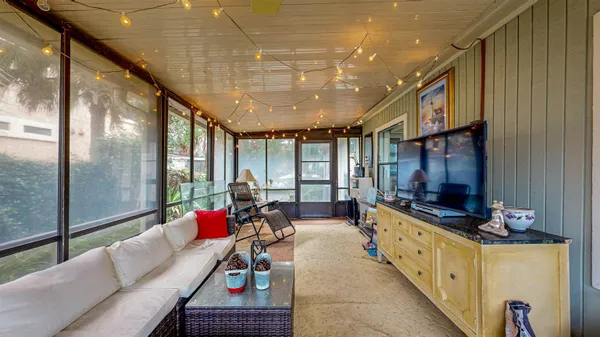 a living room with furniture windows a flat screen tv and a chandelier