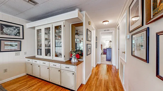 a view of a hallway with wooden floor and cabinet