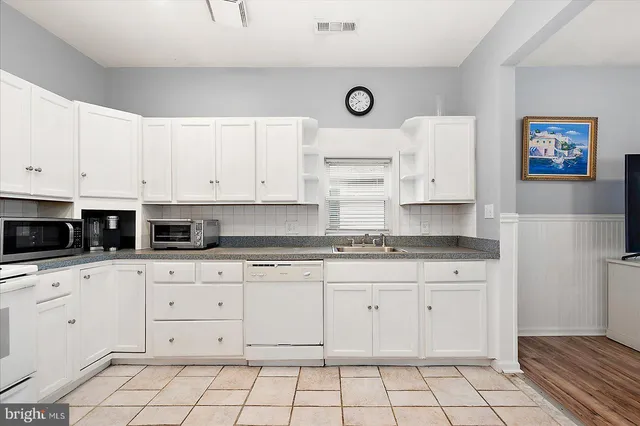 a kitchen with granite countertop white cabinets and white appliances