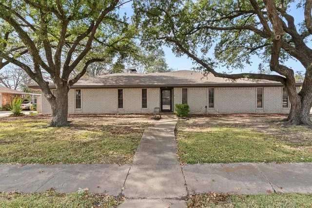 a front view of a house with a garden and tree