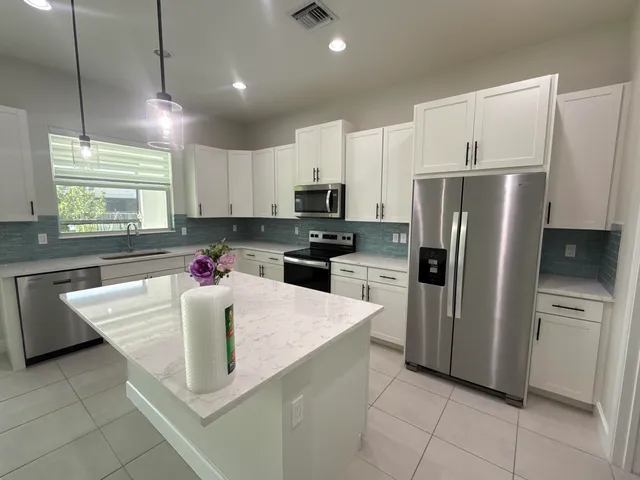 a kitchen with granite countertop a refrigerator a sink a stove a microwave a counter top space and cabinets