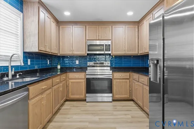 a kitchen with granite countertop cabinets stainless steel appliances a sink and a window