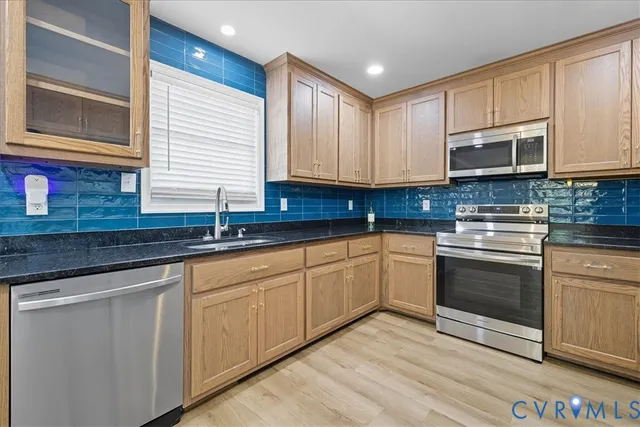 a kitchen with stainless steel appliances granite countertop a stove a sink and a refrigerator