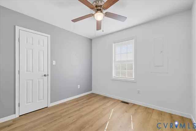 an empty room with wooden floor and ceiling fan