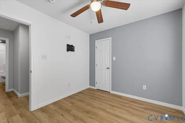 an empty room with a window and ceiling fan