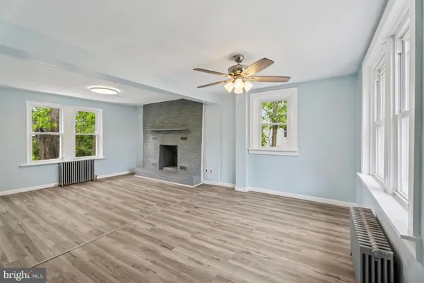 a view of an empty room with window and chandelier fan