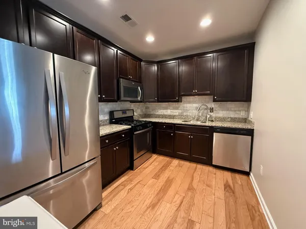 a kitchen with stainless steel appliances granite countertop a refrigerator a sink and a stove