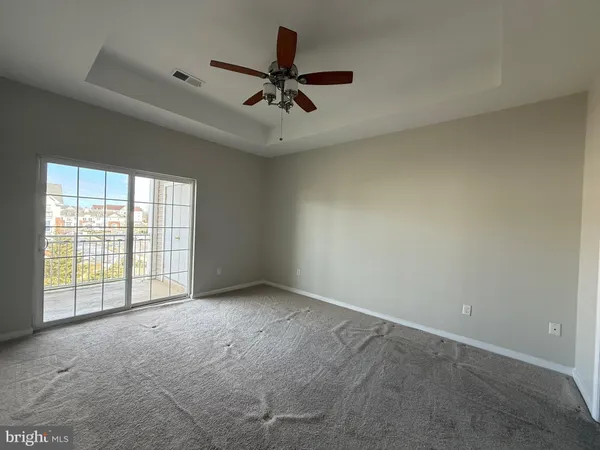 an empty room with windows and ceiling fan