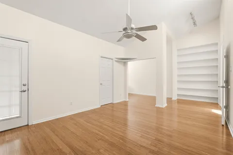 an empty room with wooden floor and fan