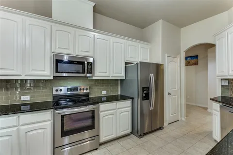 a kitchen with white cabinets and stainless steel appliances