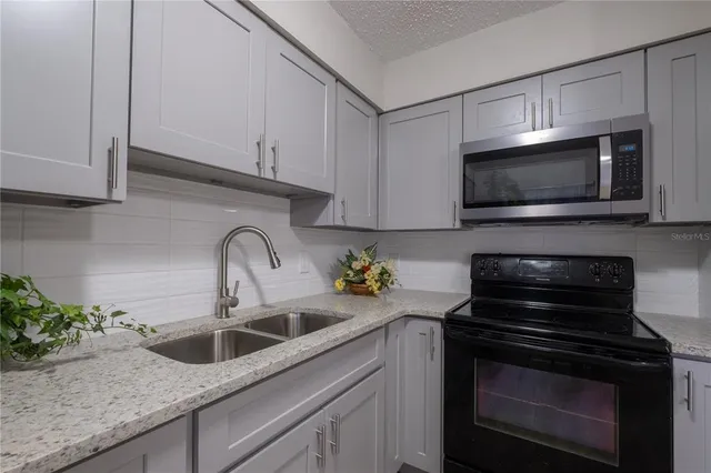 a kitchen with sink a microwave and cabinets
