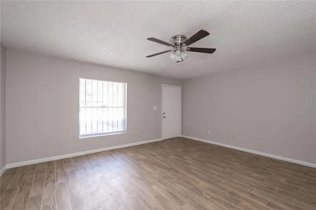 a view of empty room with wooden floor and fan