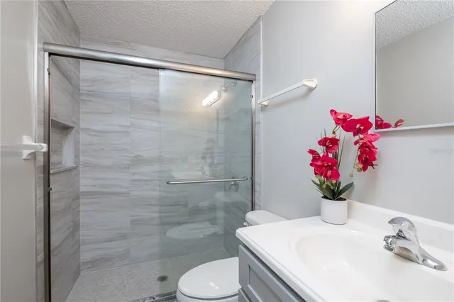 a bathroom with a shower sink vanity mirror and toilet
