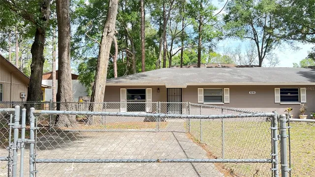 a front view of house with yard outdoor seating and trees in the background