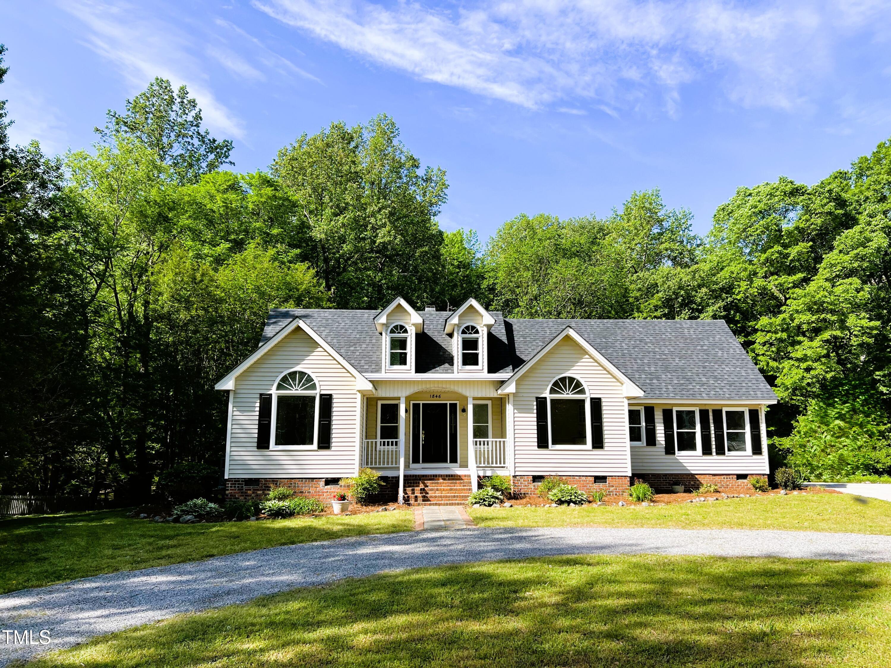 a front view of a house with a garden and trees