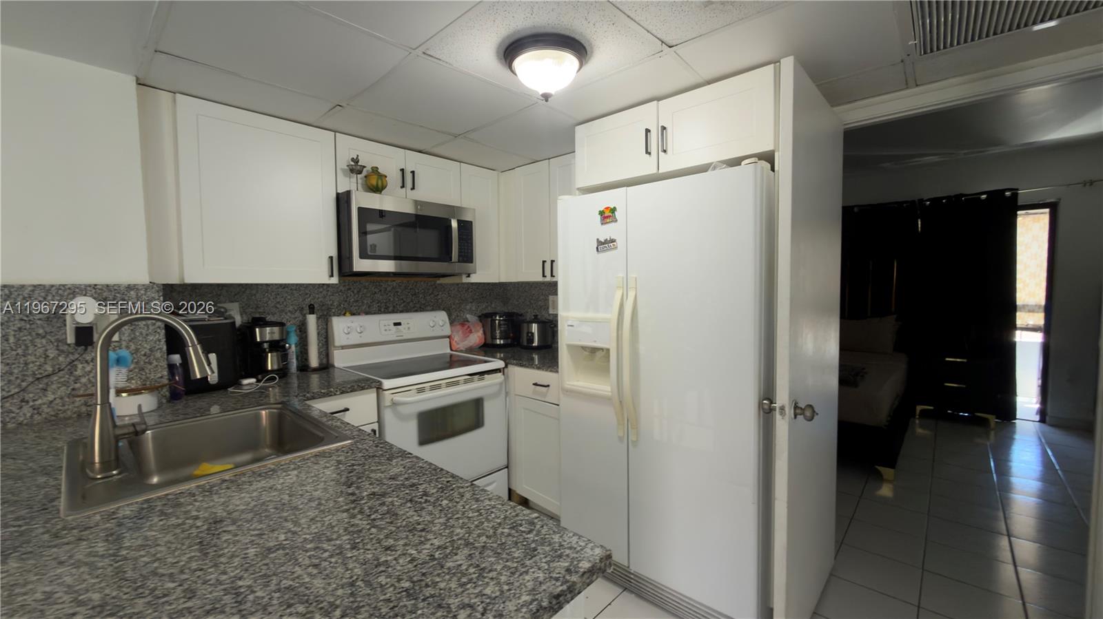 2170 West 60th Street, Unit 16205 Hialeah, FL 33016 - Photo 3 of 6 a kitchen with stainless steel appliances granite countertop a refrigerator a stove a sink a microwave and a dining table with wooden floor