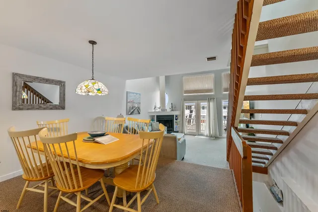 a view of a dining room and livingroom with furniture wooden floor a rug a painting and a chandelier