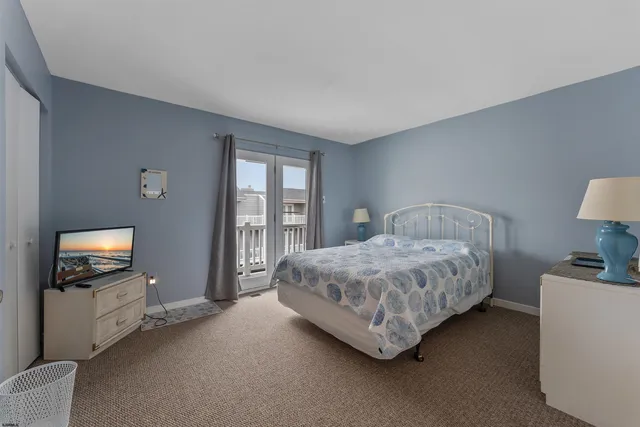 a spacious bedroom with a bed and a flat tv screen on the dresser