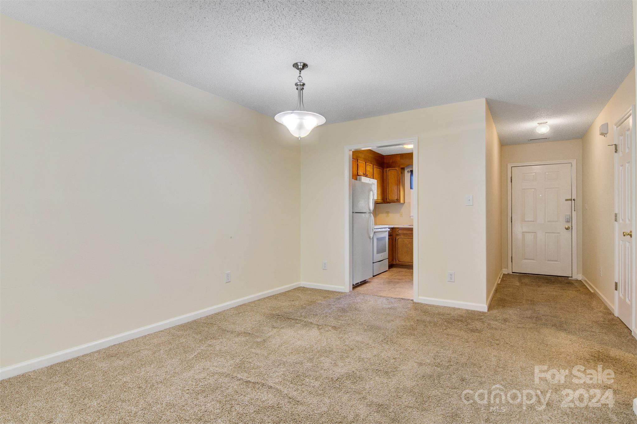 1318 5th Street Northeast Hickory, NC 28601 - Photo 12 of 27 an empty room with a chandelier fan and kitchen view
