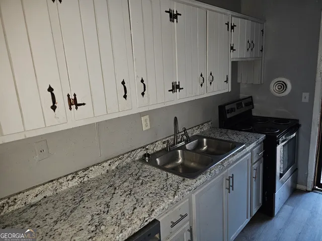 a kitchen with granite countertop white cabinets and a sink