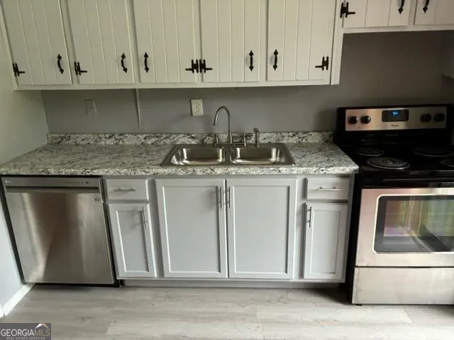 a kitchen with granite countertop a sink stove and cabinets