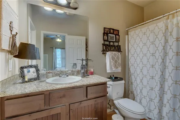 a bathroom with a granite countertop sink mirror vanity and toilet
