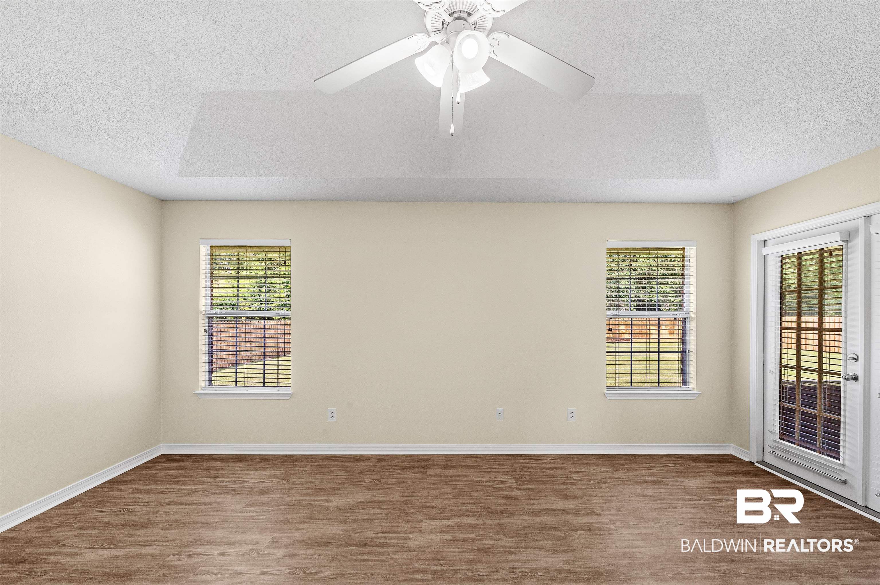 12443 Venice Boulevard Foley, AL 36535 - Photo 42 of 59 Spare room with a raised ceiling, ceiling fan, a healthy amount of sunlight, and wood-type flooring