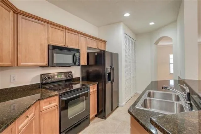 a kitchen with stainless steel appliances granite countertop a refrigerator a sink and a stove