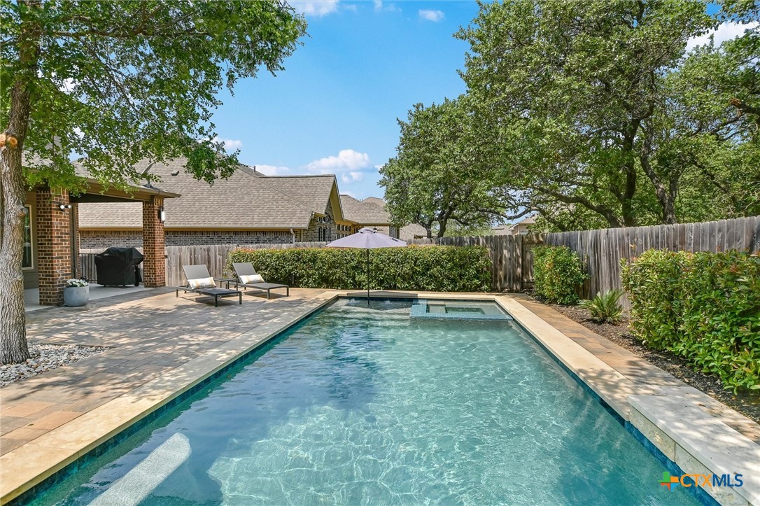 a view of a backyard patio with swimming pool and sitting space