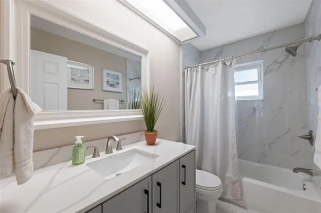 a bathroom with a granite countertop sink a toilet a mirror a vanity and shower