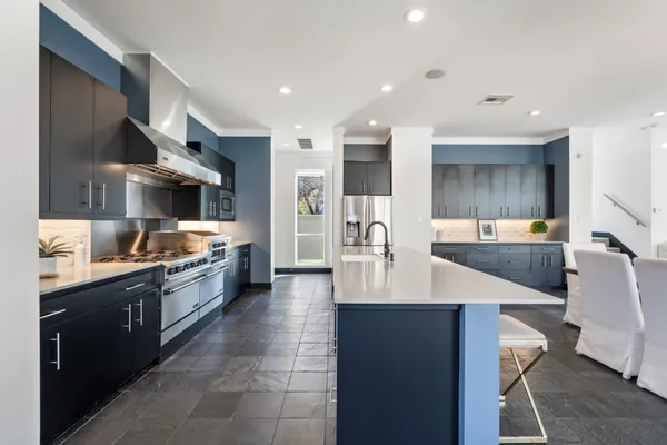 a large kitchen with stainless steel appliances a large counter top a stove and a sink