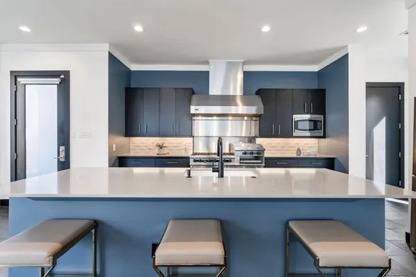 a kitchen with white cabinets and chairs