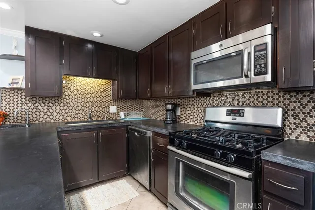 a kitchen with granite countertop a stove top oven microwave and cabinets