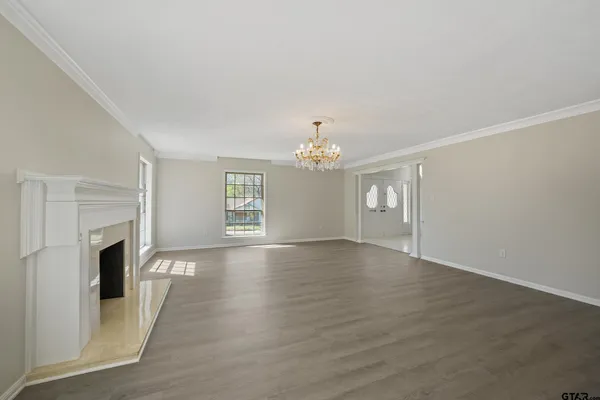 an empty room with wooden floor fireplace and windows