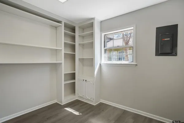 an empty room with wooden floor cabinet and windows