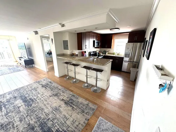 a living room with stainless steel appliances furniture a rug and a view of kitchen