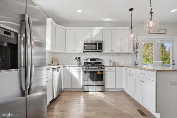 a kitchen with stainless steel appliances granite countertop a refrigerator a stove a sink and a microwave