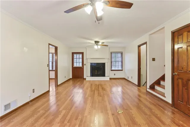 an empty room with wooden floor fireplace and windows