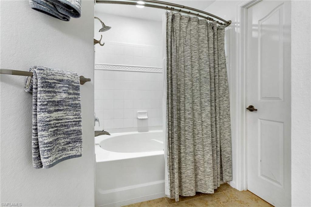 12980 Positano Circle, Unit 202 Naples, FL 34105 - Photo 18 of 27 a bathroom with a shower curtain and a sink